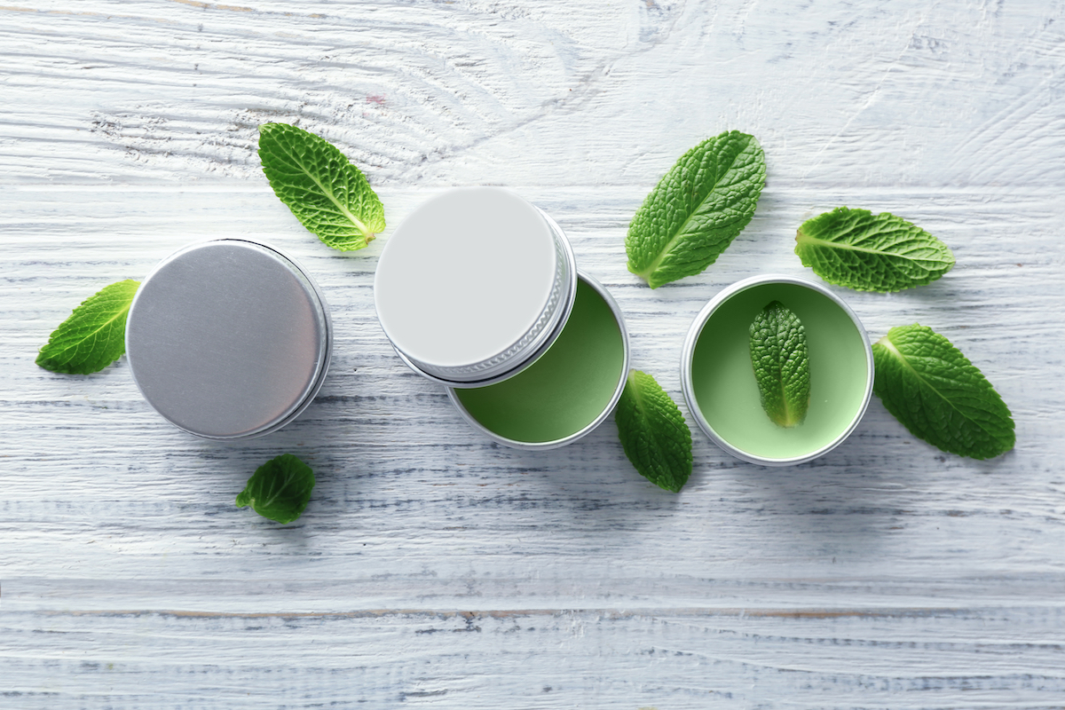 containers,with,lemon,balm,salve,and,leaves,on,wooden,table