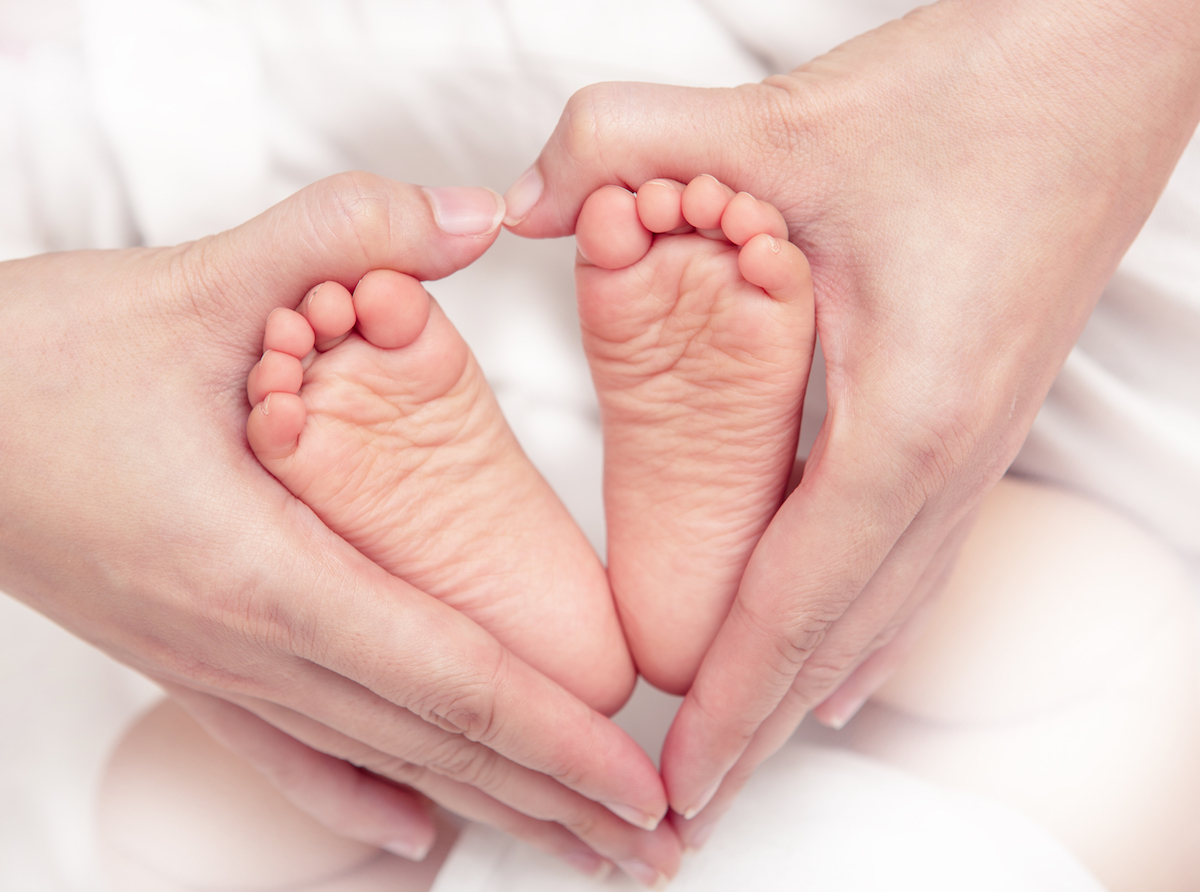 baby's,foot,in,mother,hands,closeup,on,the,bed,,new